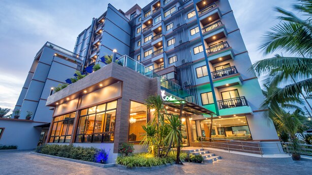 A multi-story hotel with a modern design, featuring balconies, large windows, and a well-lit entrance. - Andaman Breeze Resort - (Krabi)