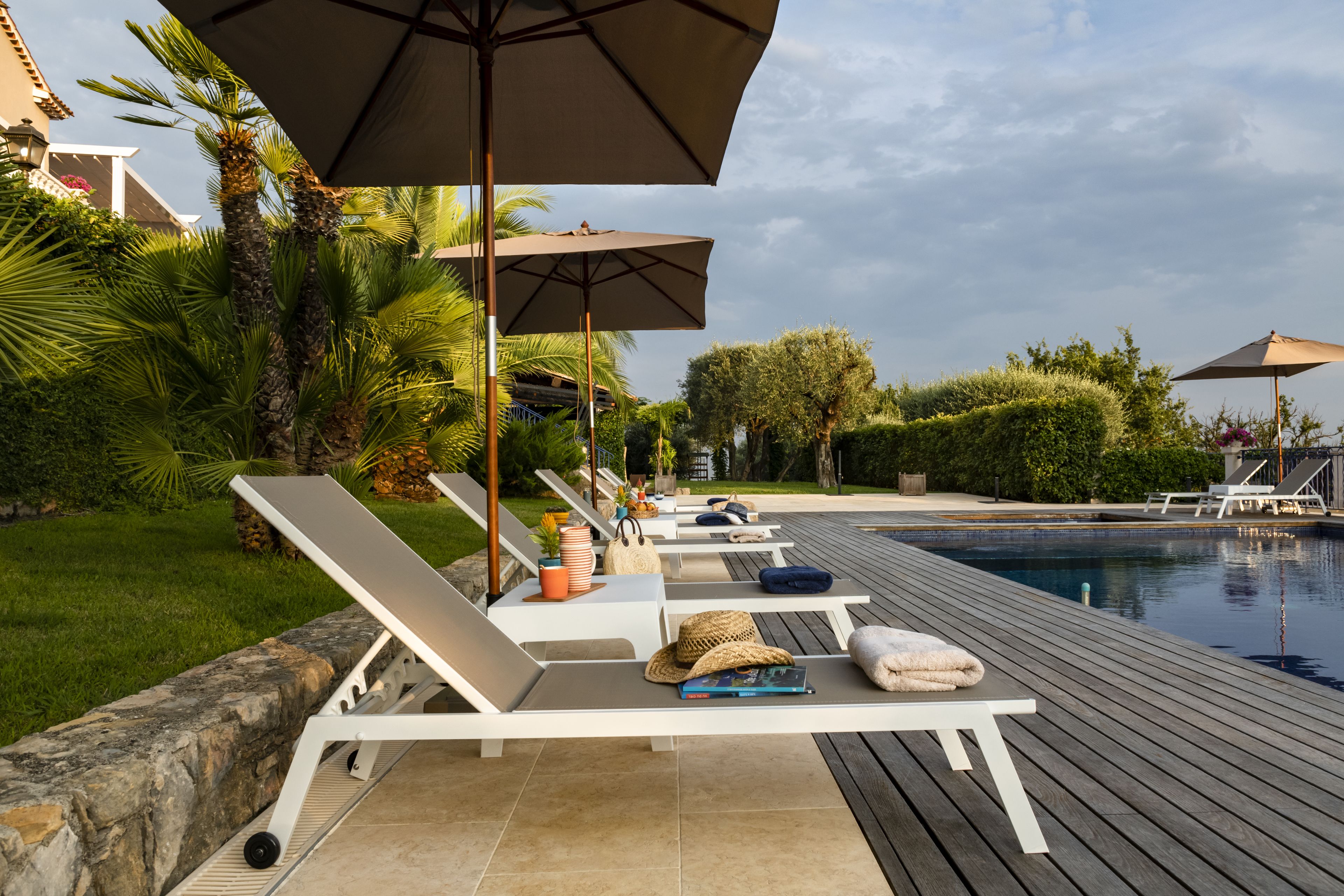 A poolside area with lounge chairs, umbrellas, and a swimming pool.