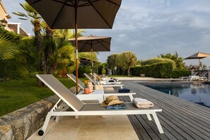 Una piscina al aire libre, tumbonas