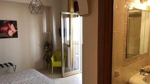 A bathroom with a large mirror, a sink, and a door leading to a balcony.