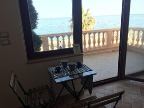 A balcony with a view of the sea, a table with cups and a sign, and a bench. - Le Camere di Rosanna (Marina di Gioiosa Ionica)