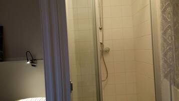 Un baño con ducha de vidrio, bañera y cama con ropa de cama a rayas.