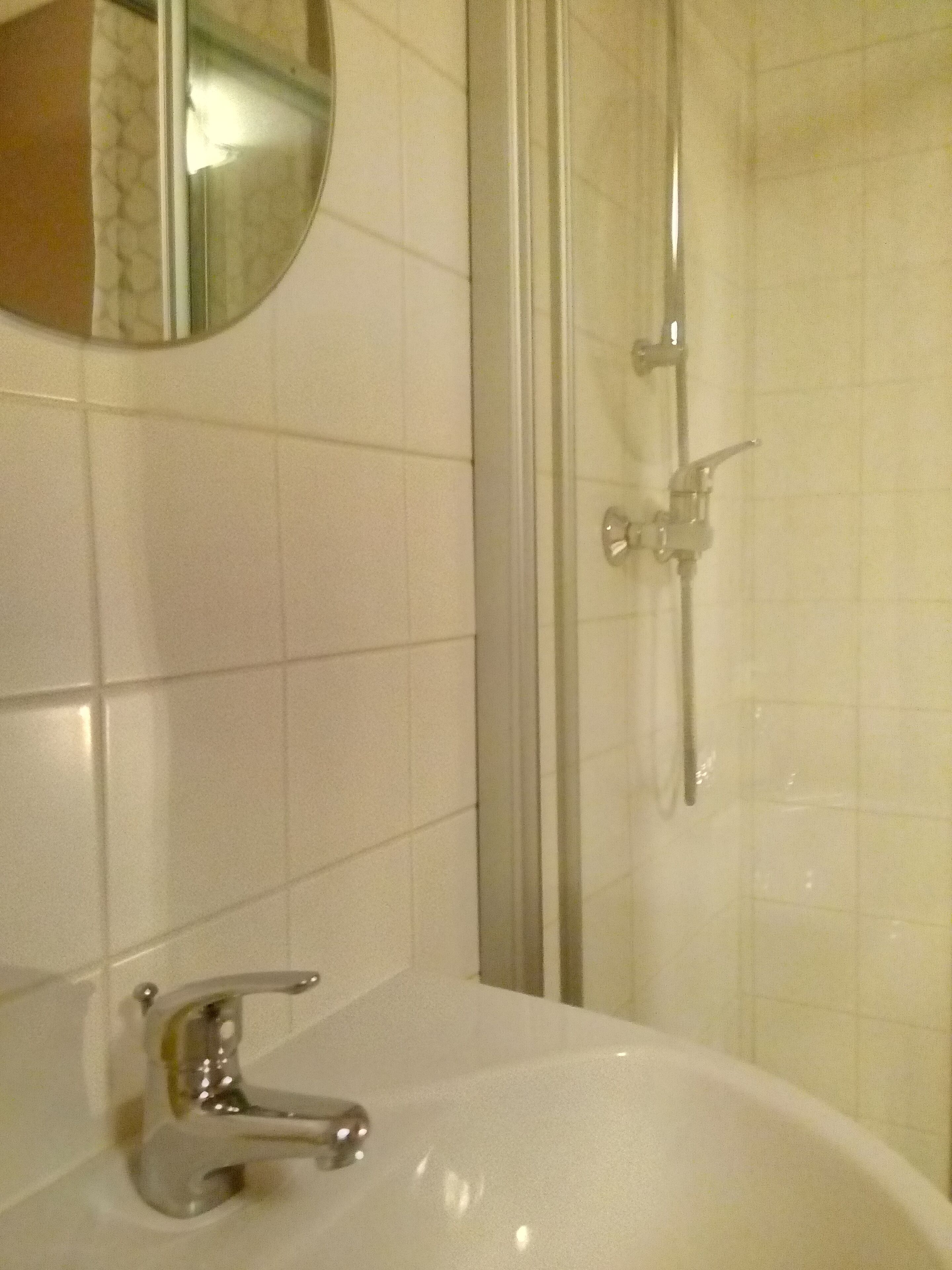 A bathroom with a white sink, a mirror, and a glass shower enclosure.