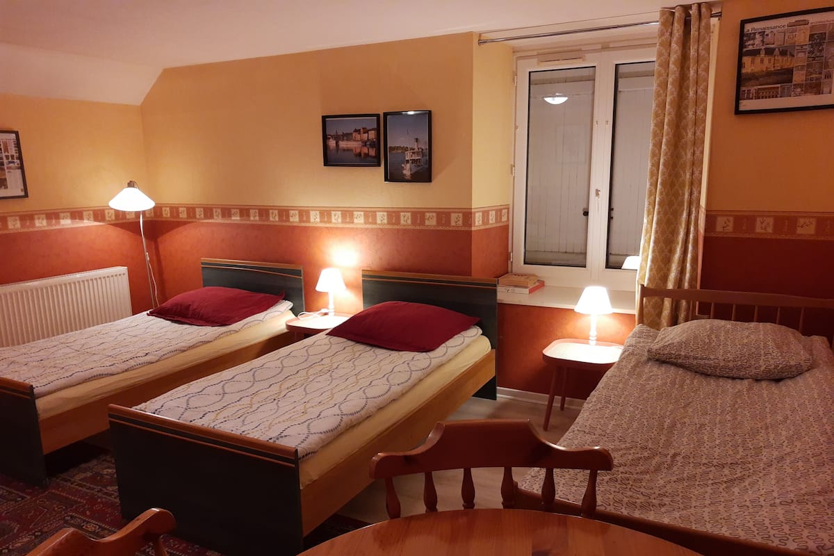 Ein Hotelzimmer mit zwei Einzelbetten, einem Holztisch und einem Fenster mit Vorhängen.