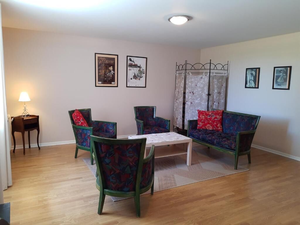 Una sala de estar con sofá, sillas, una mesa y una lámpara.