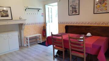 Un coin repas avec une table dressée pour deux personnes, un banc et un extincteur fixé au mur.