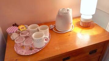 A wooden table with a tea set, including cups and a teapot, and a lamp.