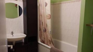 A bathroom with a sink, mirror, dark cabinet, shower curtain, and a towel hanging on the wall.