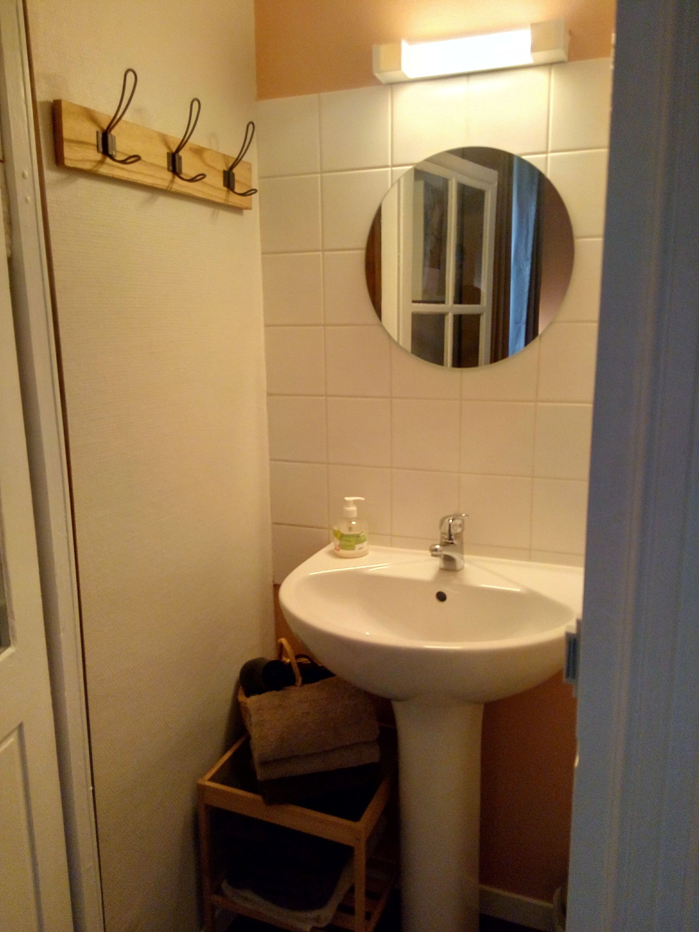 A bathroom with a white sink, a mirror, and a towel rack.