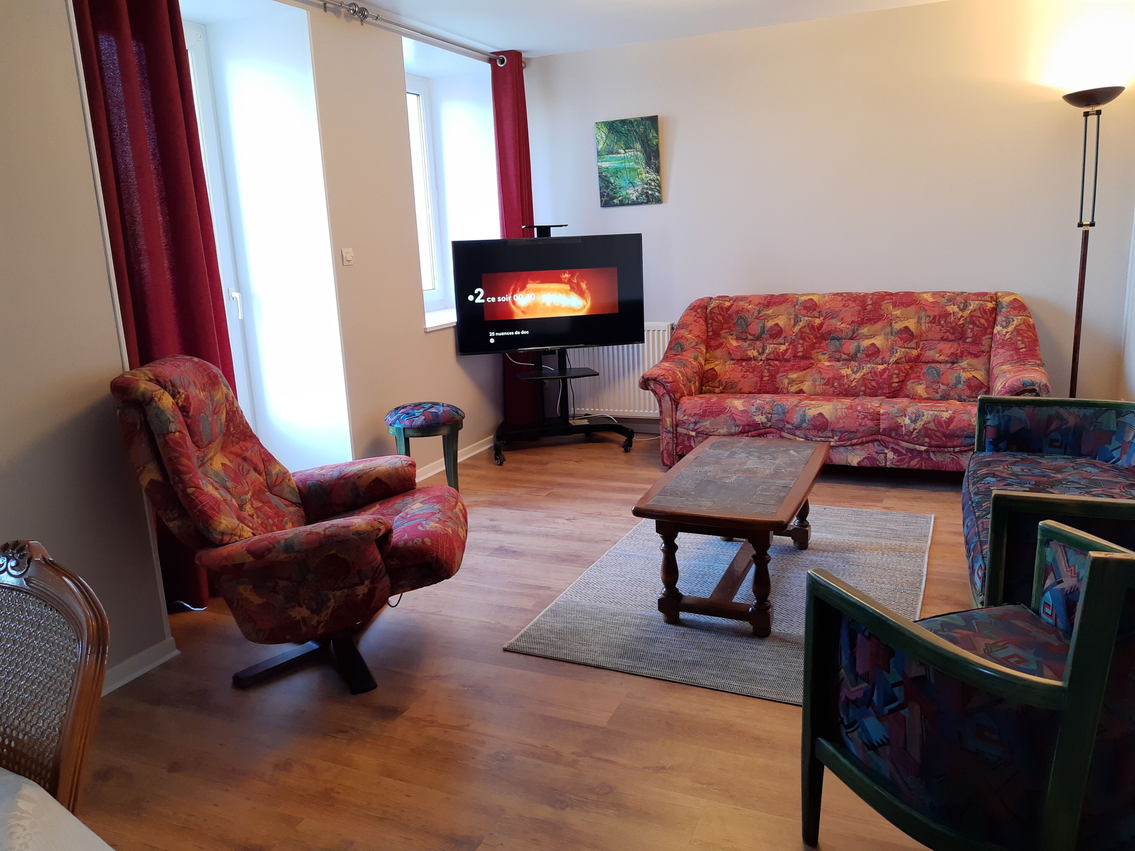 A living room with a sofa, armchair, coffee table, and a television.