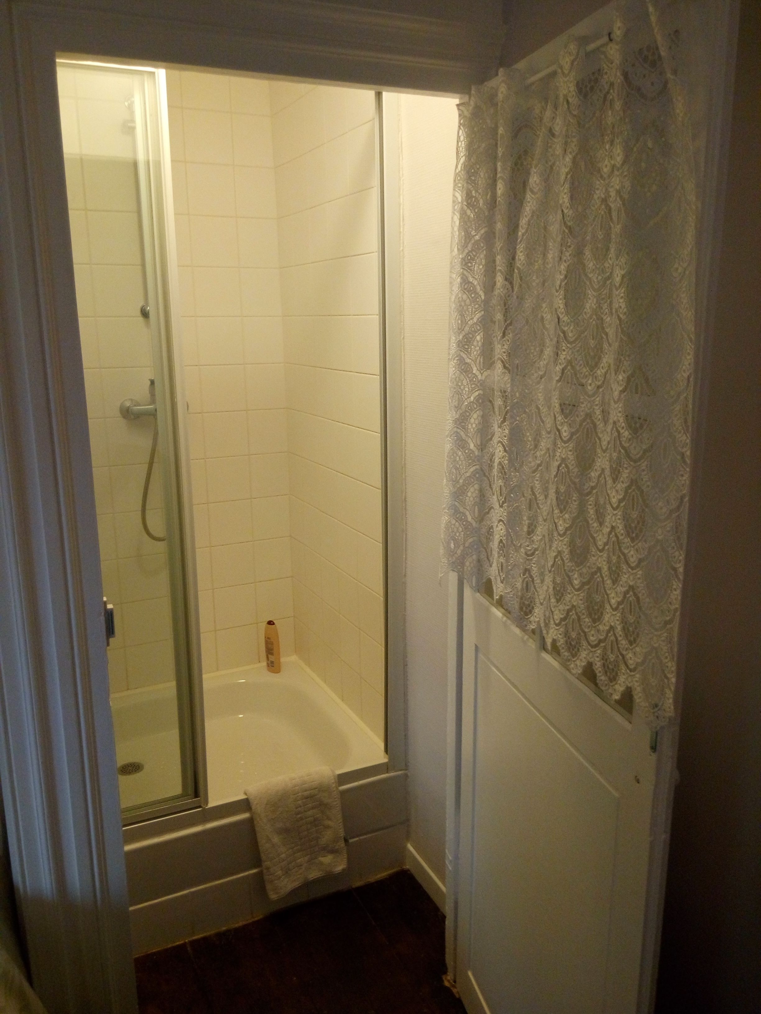 A bathroom with a shower, a bathtub, and a towel hanging on the wall.