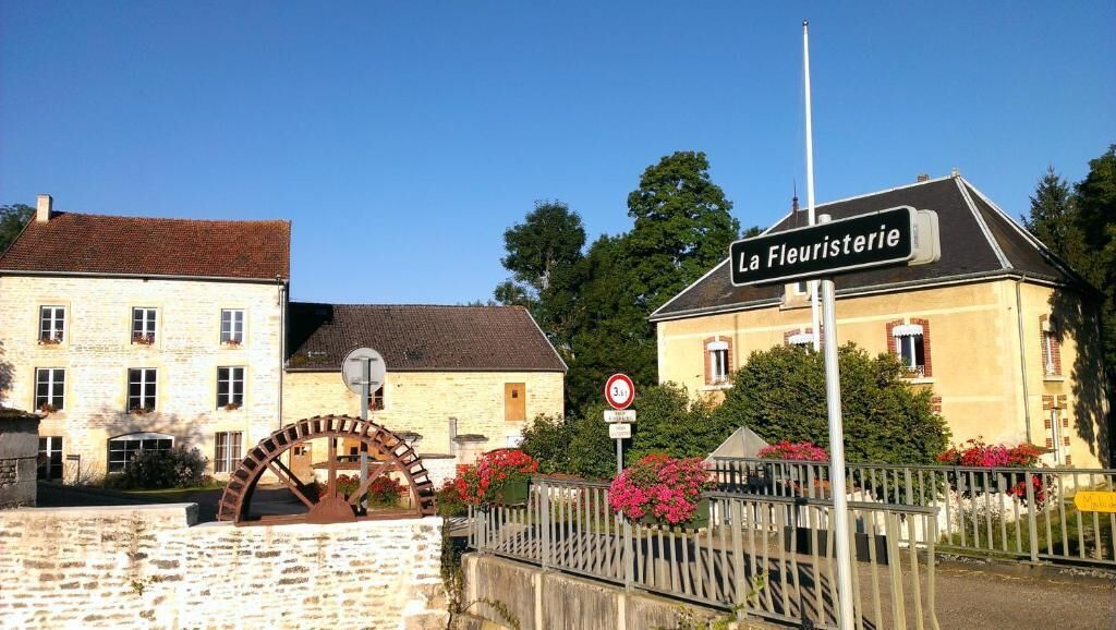 Een historisch pand met een watermolen en een bord waarop 'La Fleuristerie' staat.
