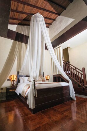 A four-poster canopy bed with a wooden headboard, a nightstand with a lamp, and a staircase in the background. - Floral Hotel Huzhou Shenanxun Chenxiang (Huzhou)