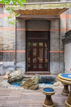 A traditional building with a tiled entrance, a wooden door, and a small outdoor water feature with rocks and a fountain. - Floral Hotel Huzhou Shenanxun Chenxiang (Huzhou)