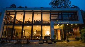 A modern building with large windows, a visible dining area with tables and chairs, and a sign indicating a restaurant or cafe. - Floral Hotel Moganshan Cuiyu Resort (Huzhou)