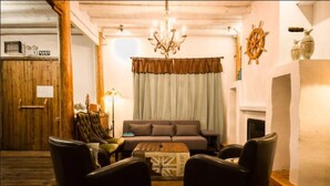 A cozy living room with a sofa, armchairs, a wooden coffee table, and a fireplace. - Floral Hotel Moganshan Cuiyu Resort (Huzhou)