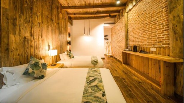 A wooden room with two beds, a brick wall, and a wooden ceiling. - Floral Hotel Moganshan Cuiyu Resort (Huzhou)