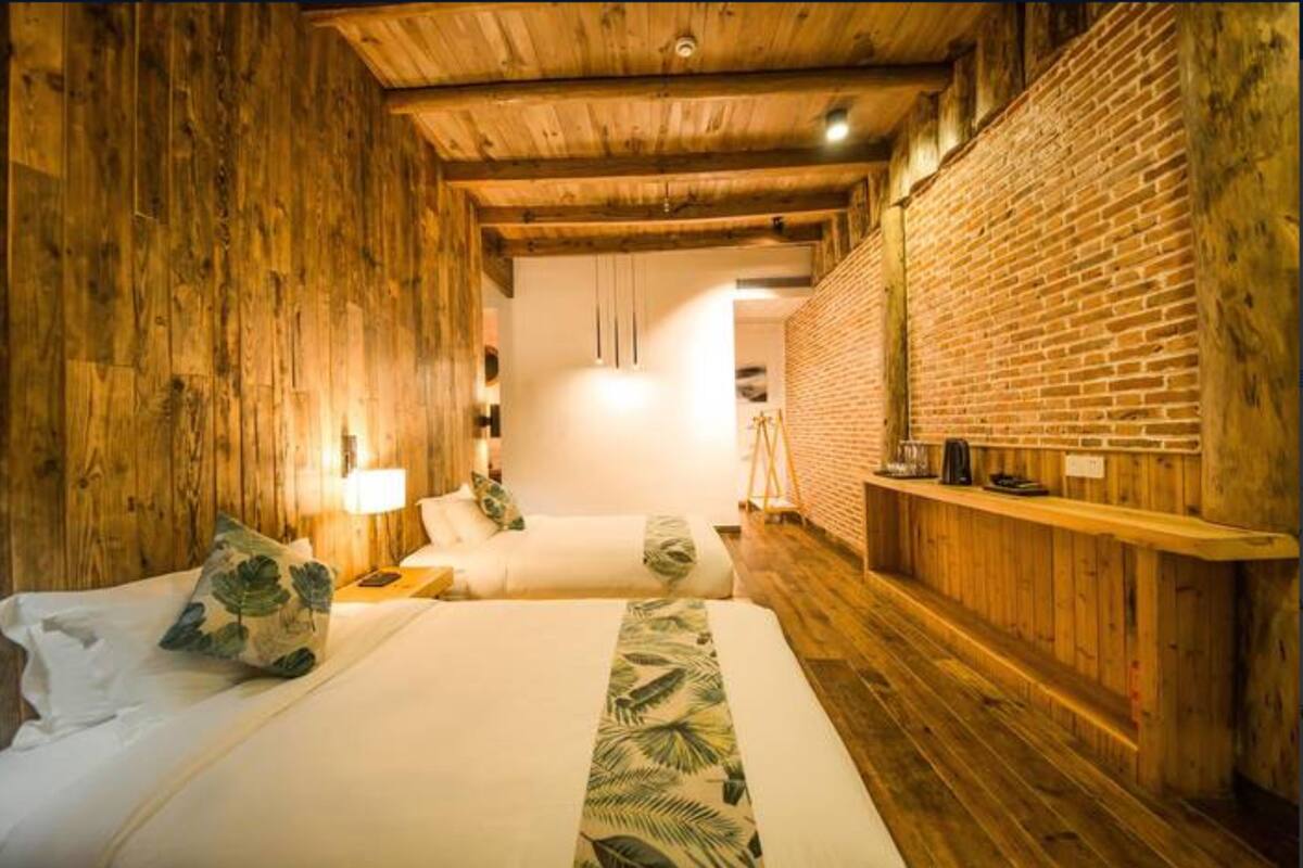 A wooden room with two beds, a brick wall, and a wooden ceiling.