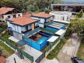 A modern multi-story house with a rooftop pool, surrounded by greenery and other residential buildings. - Zumrut Villas (Sapanca)