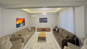 A modern living room with two sofas, a coffee table, and a TV mounted on the wall. - Zumrut Villas (Sapanca)