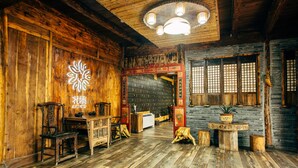 A traditional wooden interior with a wooden ceiling, a large wooden door, and a stone wall. - Floral Hotel Moganshan Yaozhuang (Huzhou)