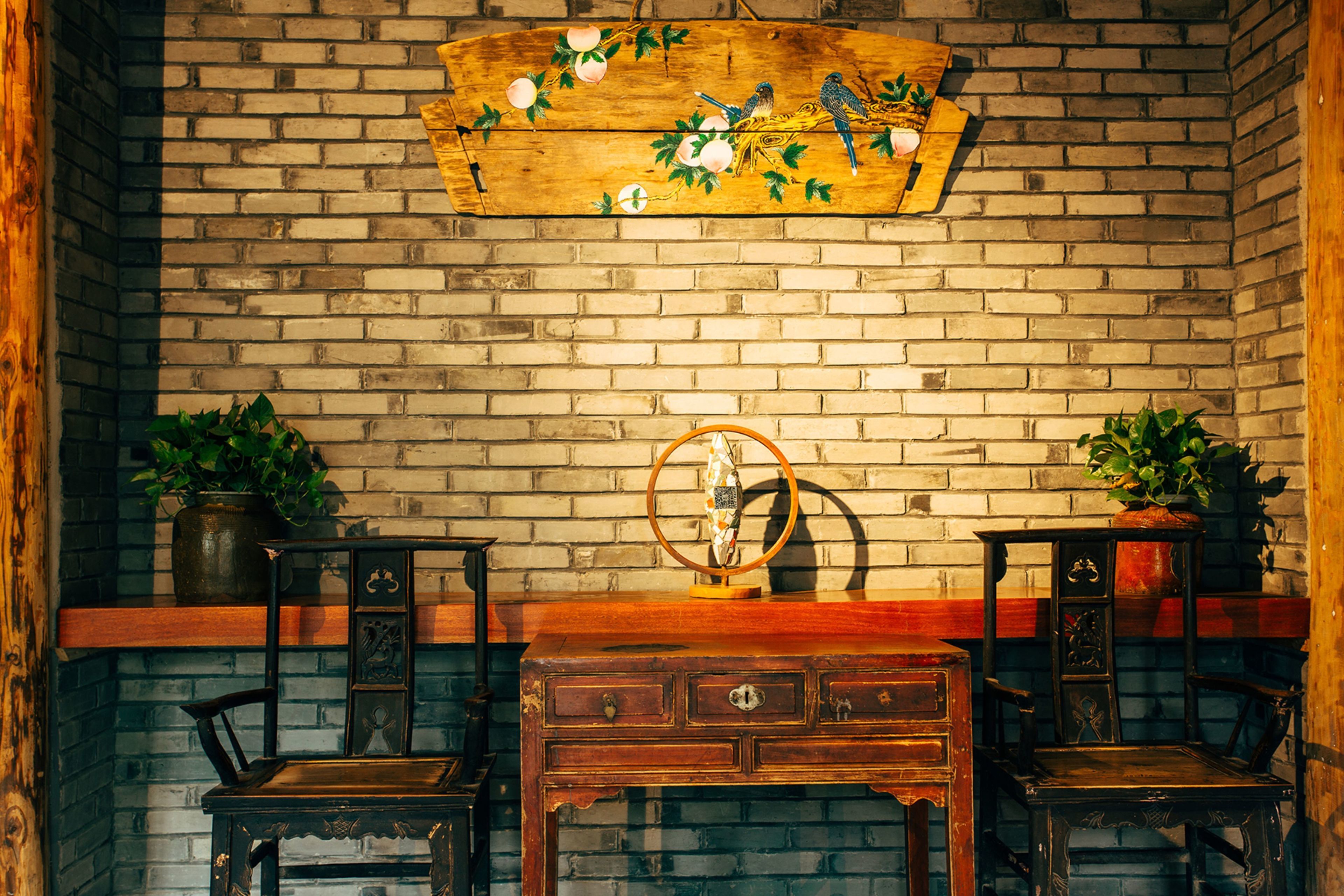A rustic room with a brick wall, wooden furniture, and decorative elements like a wooden sign with birds and plants.