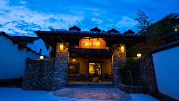 A traditional building with stone pillars and a tiled roof, featuring a sign with Chinese characters. - Floral Hotel Moganshan Yaozhuang (Huzhou)