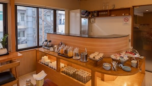 Una barra de desayuno con diferentes alimentos, una estación de café y un cartel de prohibido fumar.