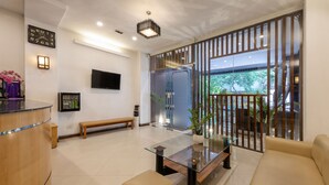 Una sala de estar moderna con una mesa de centro de vidrio, un sofá, un banco y un televisor montado en la pared.