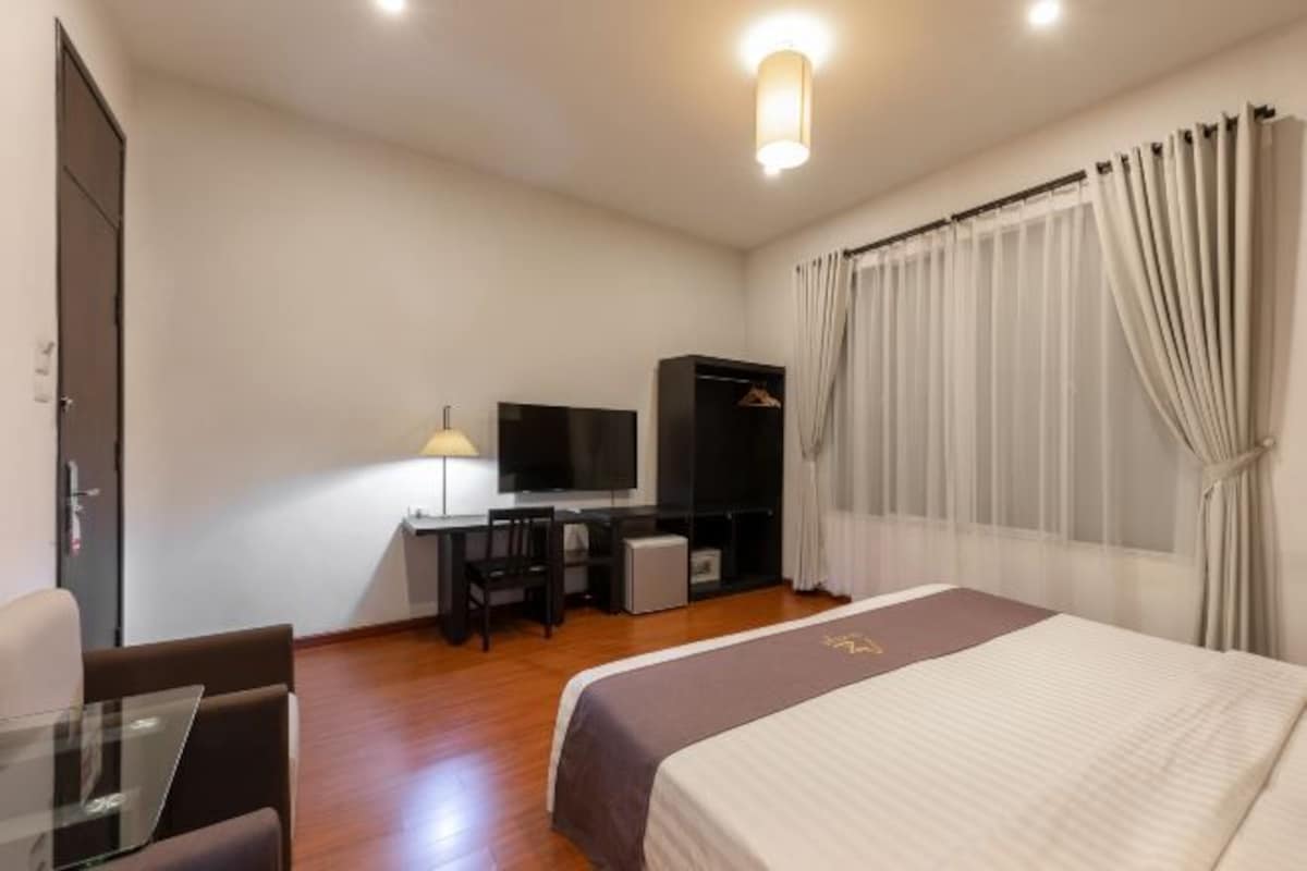 Une chambre d’hôtel comprenant un lit, un bureau avec un ordinateur, une télévision et une armoire.