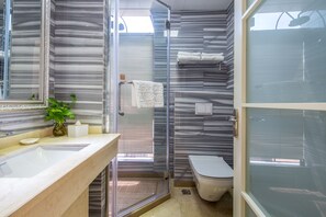 Une salle de bain avec un meuble-lavabo en marbre, une cabine de douche en verre et des toilettes.