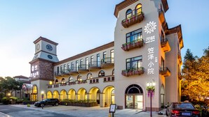 Un hôtel doté d’une tour centrale, de nombreux balcons ornés de plantes et d’une enseigne avec des caractères chinois.