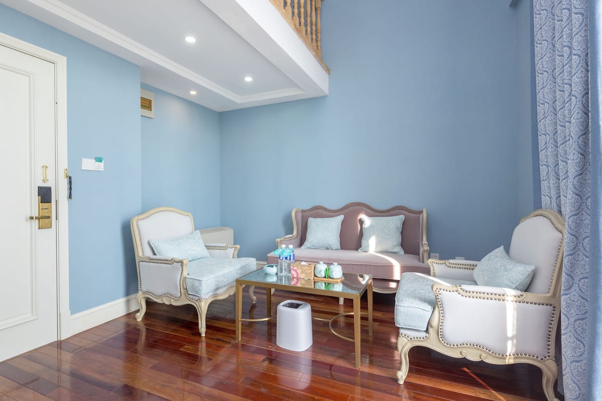 Amplio salón con techo alto, una escalera de madera y vista al piso superior.