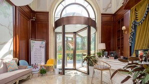 Un hall d'entrée doté d'une porte tournante, d'un comptoir de réception, d'un espace salon et d'une grande fenêtre.