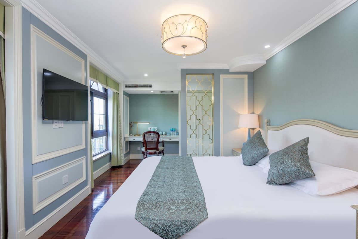 Una habitación de hotel con una cama grande, un escritorio y una televisión.