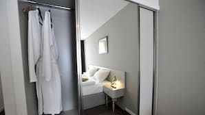Une chambre d’hôtel équipée d’un lit, d’une table de chevet et d’une armoire avec des peignoirs.