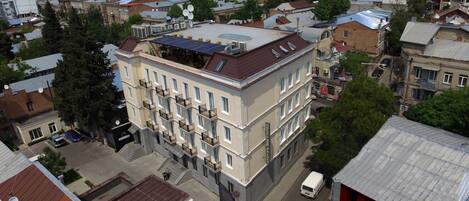 Un edificio de varios pisos con balcones, un estacionamiento y vista a la calle.