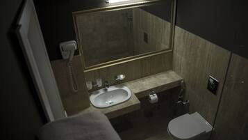 A compact bathroom with a sink, toilet, and a large mirror.