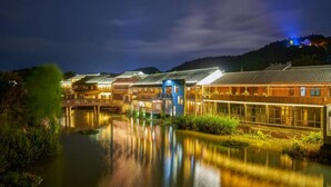 Ein traditionelles japanisches Ryokan mit einem Fluss davor, Holzbauten und einer Brücke.