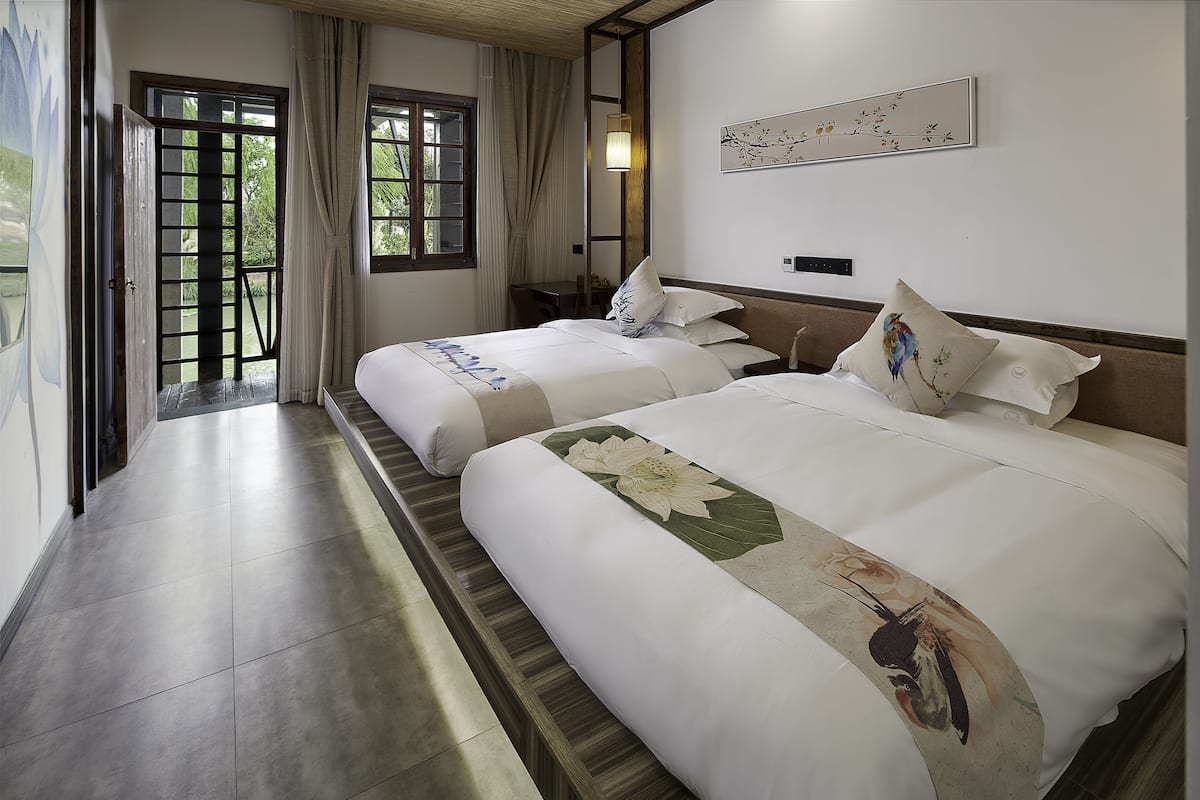 Ein Hotelzimmer mit zwei Betten, einem Schreibtisch und Blick ins Freie.