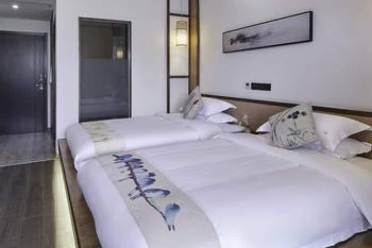 Ein modernes Hotelzimmer mit einem großen Bett, einem Nachttisch und einem gerahmten Kunstwerk an der Wand.