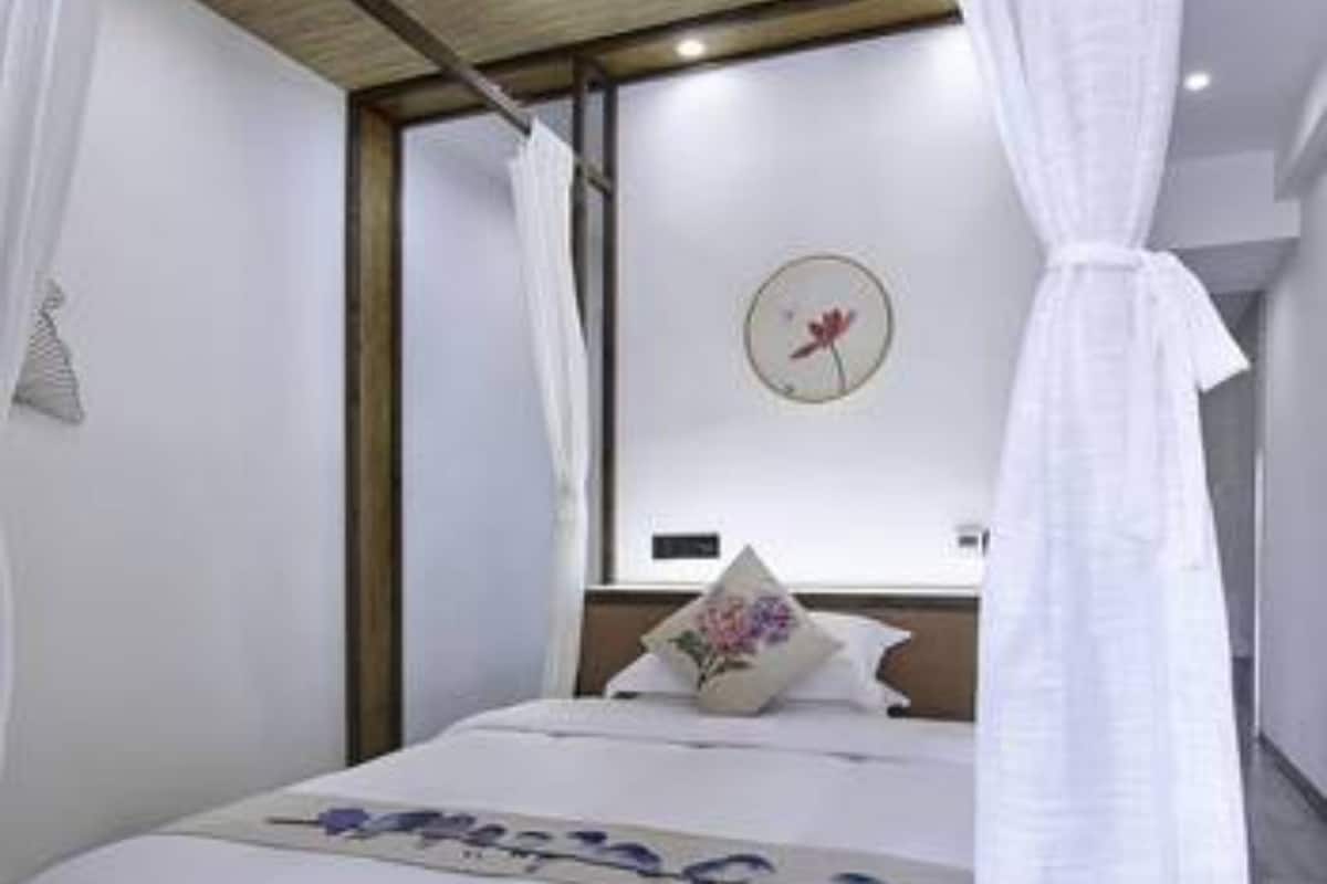 Ein Schlafzimmer mit einem Bett, einer Wanduhr und einem Fenster mit Vorhängen.