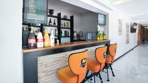 A bar area with a beverage menu, shelves with bottles, and orange bar chairs. - OYO 195 Ranchotel - Binan (Biñan City)
