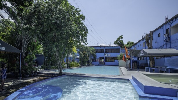 A swimming pool with clear water, surrounded by buildings and trees. - OYO 195 Ranchotel - Binan (Biñan City)