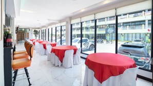 A restaurant with tables covered in red and white tablecloths, large windows with a view of the street, and a clean, modern interior. - OYO 195 Ranchotel - Binan (Biñan City)