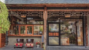 A building with a wooden facade, large windows, and a seating area with two chairs and a table. - That Mountain That Shed (Huzhou)