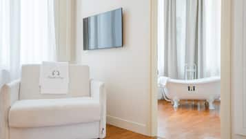 Relax in a stylish space with a plush sofa, flat-screen TV, and classic bathtub.
