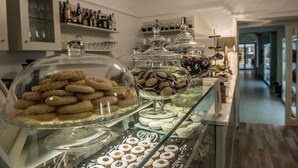 A dessert display with various pastries and a selection of bottles on shelves. - Palazzo Cini Luxury Rooms In Pisa (Pisa)