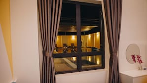 Een hotelkamer met een bed, een bureau, een spiegel en een raam met gordijnen.