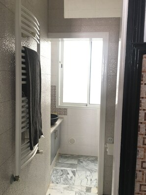 Une petite salle de bain avec une fenêtre, un porte-serviettes et un lavabo.